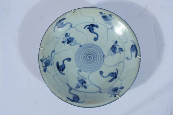 CHINA TELLER, blau glasiert, vermutlich ausgehende Ming-Dynastie d.h. 16./17.Jh. Rückseitig bezeichnet. Blaue Spirale zentriert in der Tellerfahne, umgeben von weiteren Wirbel- und Blumenmustern. Sehr schweres und gröber gearbeitetes Porzellan, auch in der Bemalung weniger detailliert, typisch für Waren aus den ländlicheren Provinzen der Ming-Epoche. D 17 cm.