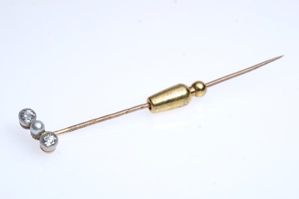 Krawattennadel, besetzt mit kleiner Perle, flankiert von zwei Brillanten, jeweils um 0,04ct. Fassung und Nadel mind. 585er Gold. Länge 6,5 cm, 2,61g.