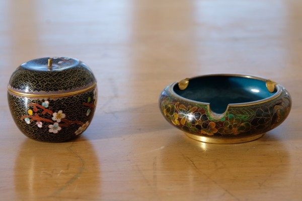 Japanisches Cloisonné-Lot: Aschenbecher und Deckeldose. Der Aschenbecher in rotbraun, blaues Inneres und Goldrand. Florale Verzierungen. Durchmesser: 11 cm. Höhe: 4 cm.